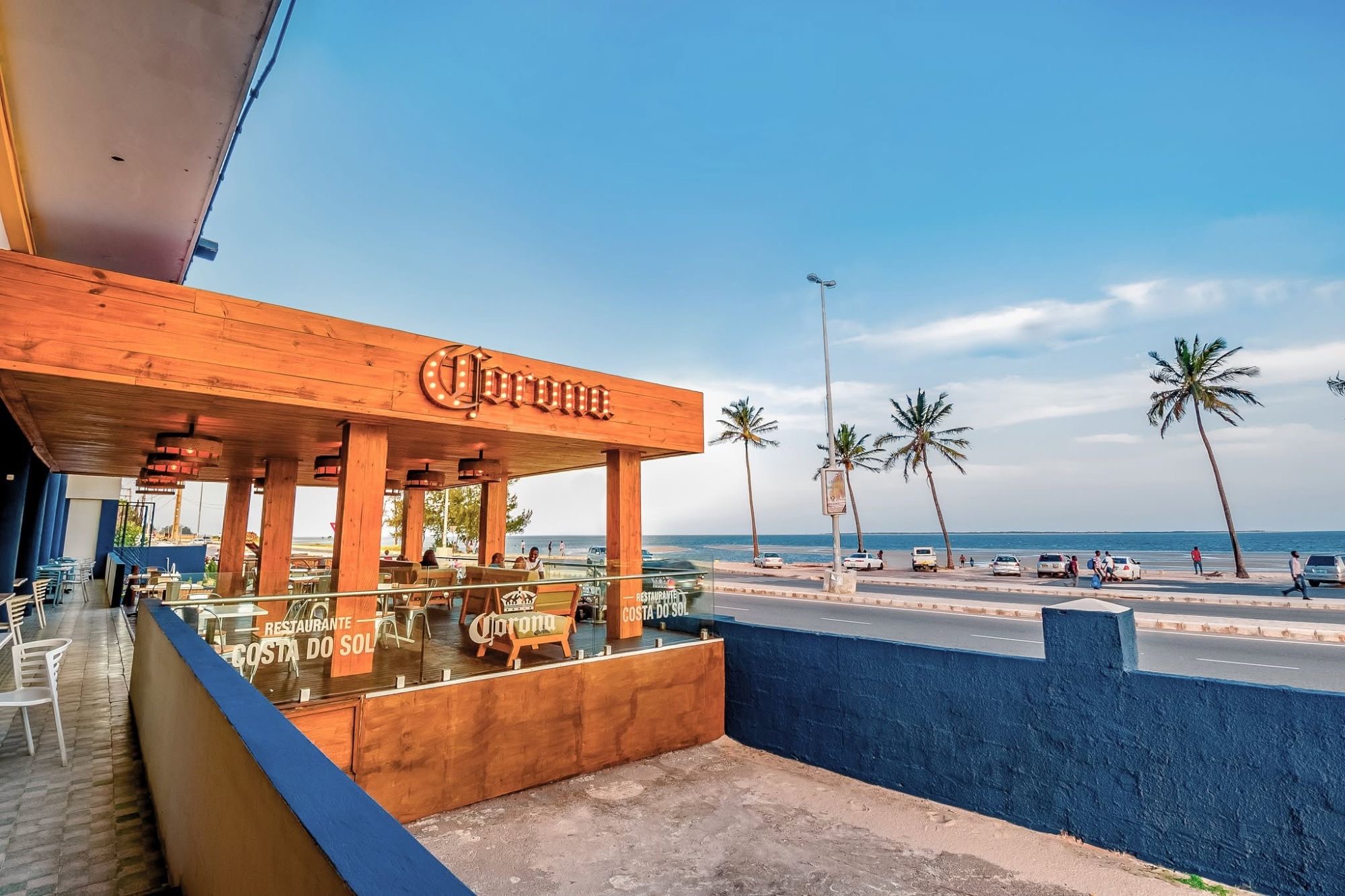 A esplanada do Restaurante Costa do Sol, com a Avenida da Marginal, as palmeiras e a baía de Maputo